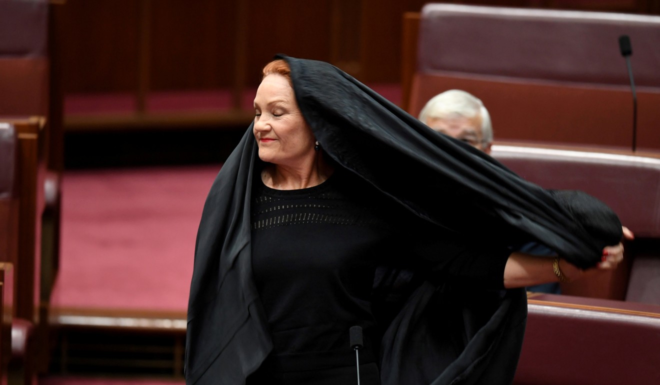 Senator Pauline Hanson pulls off a burqa in the Senate chamber at Parliament House in Canberra, Australia. Photo: Reuters
