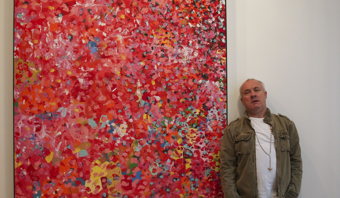 Hirst next to one of his spot paintings. Photo: K.Y. Cheng