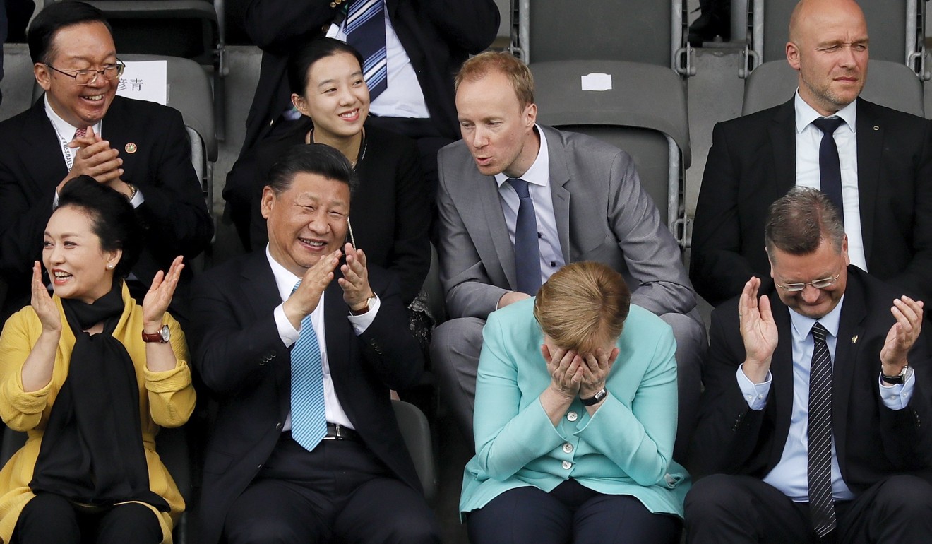 Visiting President Xi Jinping and first lady Peng Liyuan cheer while German Chancellor Angela Merkel covers her face, during an under-12 soccer game between German and Chinese children in Berlin on July 5. Also applauding in the front row is Reinhard Grindel, president of the German Football Association. Photo: EPA