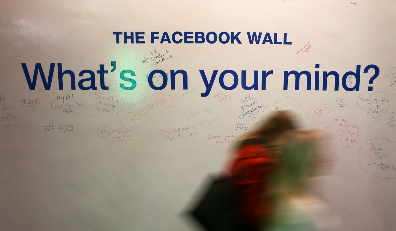 Employees walk past the Facebook Wall in London. Photo: AFP
