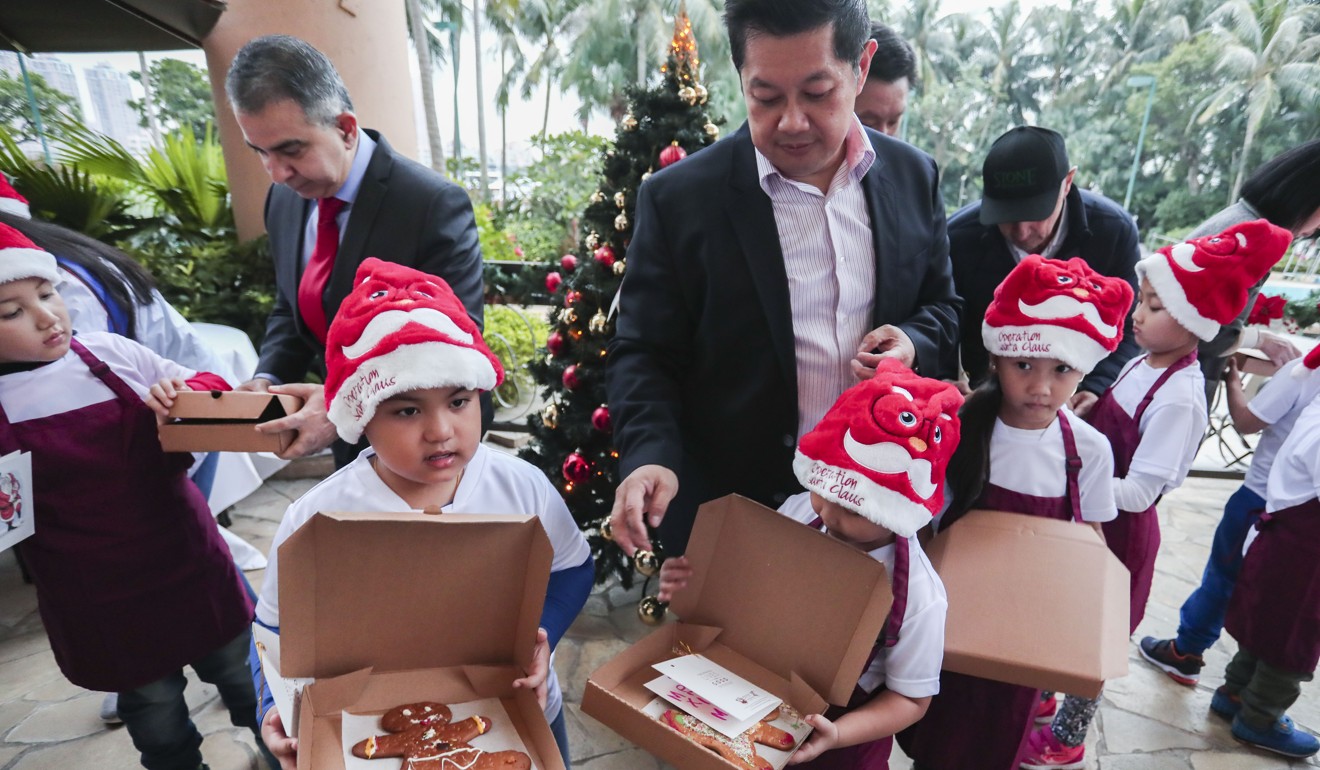 Nepalese children from the Integrated Brilliant Education Trust show off their gingerbread creations with Royal Pacific Hotel and Towers general manager Kevin Chuc (centre). Photo Jonathan Wong