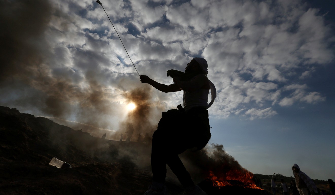 A Palestinian protester uses a sling to hurl stones towards Israeli troops during clashes near the border with Israel in the central Gaza Strip. Photo: Reuter