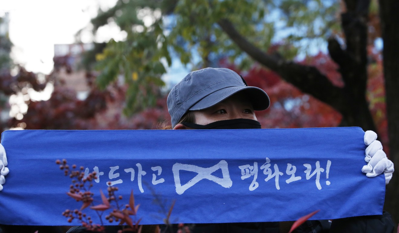 A South Korean protester holds a banners reading “Get thee gone THAAD and Come on Peace”. Photo: EPA