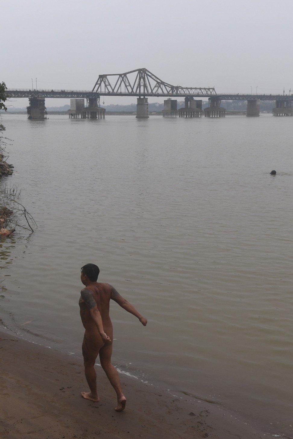 A nudist takes a walk and a stretch near Hanoi’s 115-year-old Long Bien Bridge. Photo: AFP