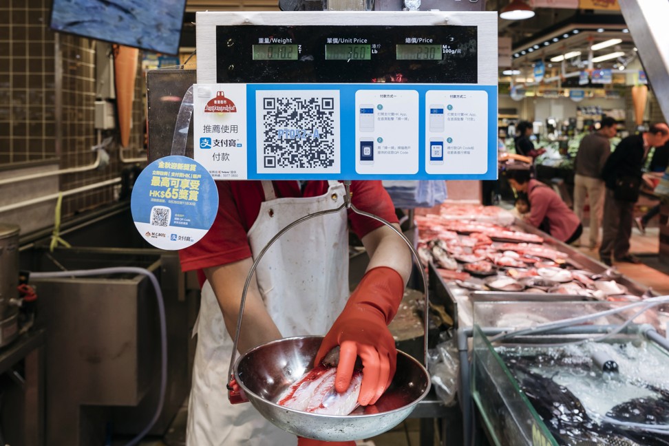 A vendor weights a piece of fish as a merchant quick response (QR) code and payment instructions for Ant Financial Services Group's Alipay, an affiliate of Alibaba Group Holding Ltd., are displayed at a fish stall inside MC Box Po Tat Market in Hong Kong. Ant Financial, which has been valued as high as $75 billion, is the world's most valuable closely held fintech company. Photo: Bloomberg