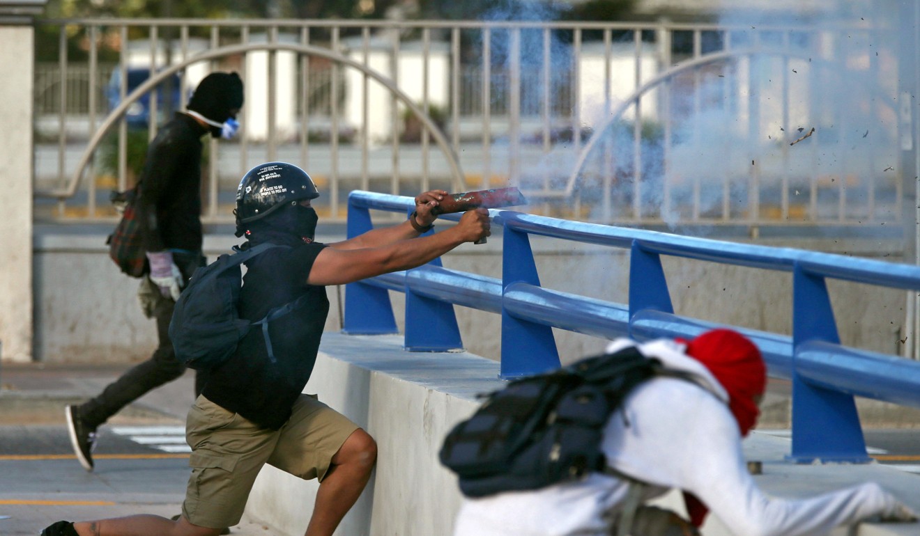A demonstrator fires a home-made mortar towards police. Photo: Reuters