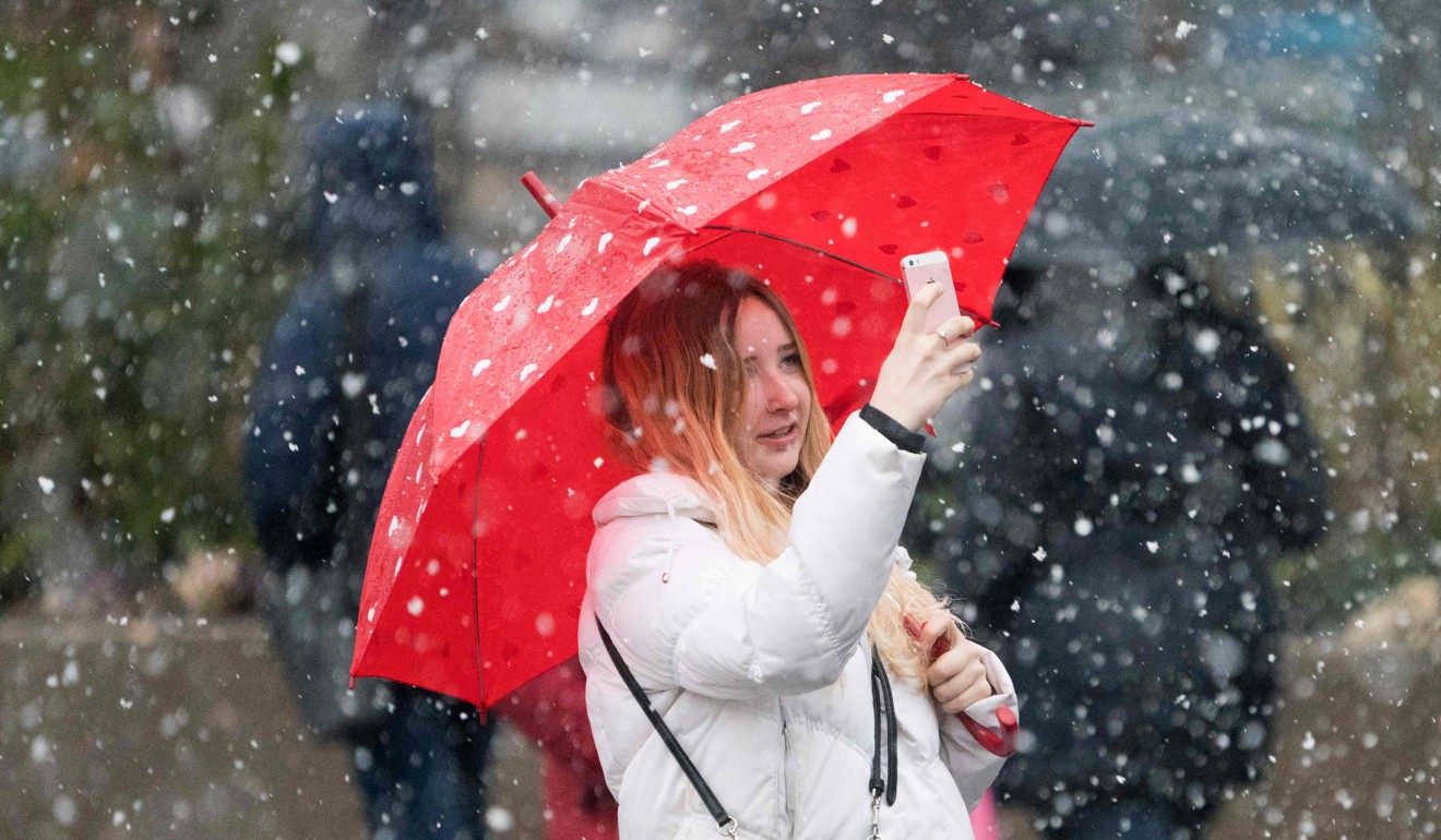A woman takes photos with her cell phone as heavy snow falls on March 7, 2018 at Union Square in New York. Hundreds of flights were cancelled Wednesday morning to and from New York airports as the region braced itself for heavy snowfall. Photo: AFP