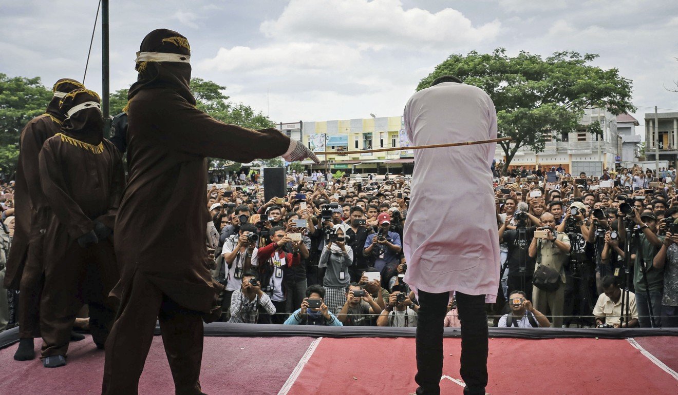 A sharia law official canes a man convicted of gay sex outside a mosque in Aceh province, Indonesia. Photo: AP