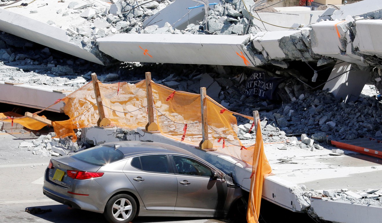 A damaged car is seen partially trapped as workers remove debris from a collapsed pedestrian bridge at Florida International University in Miami. Photo: Reuters