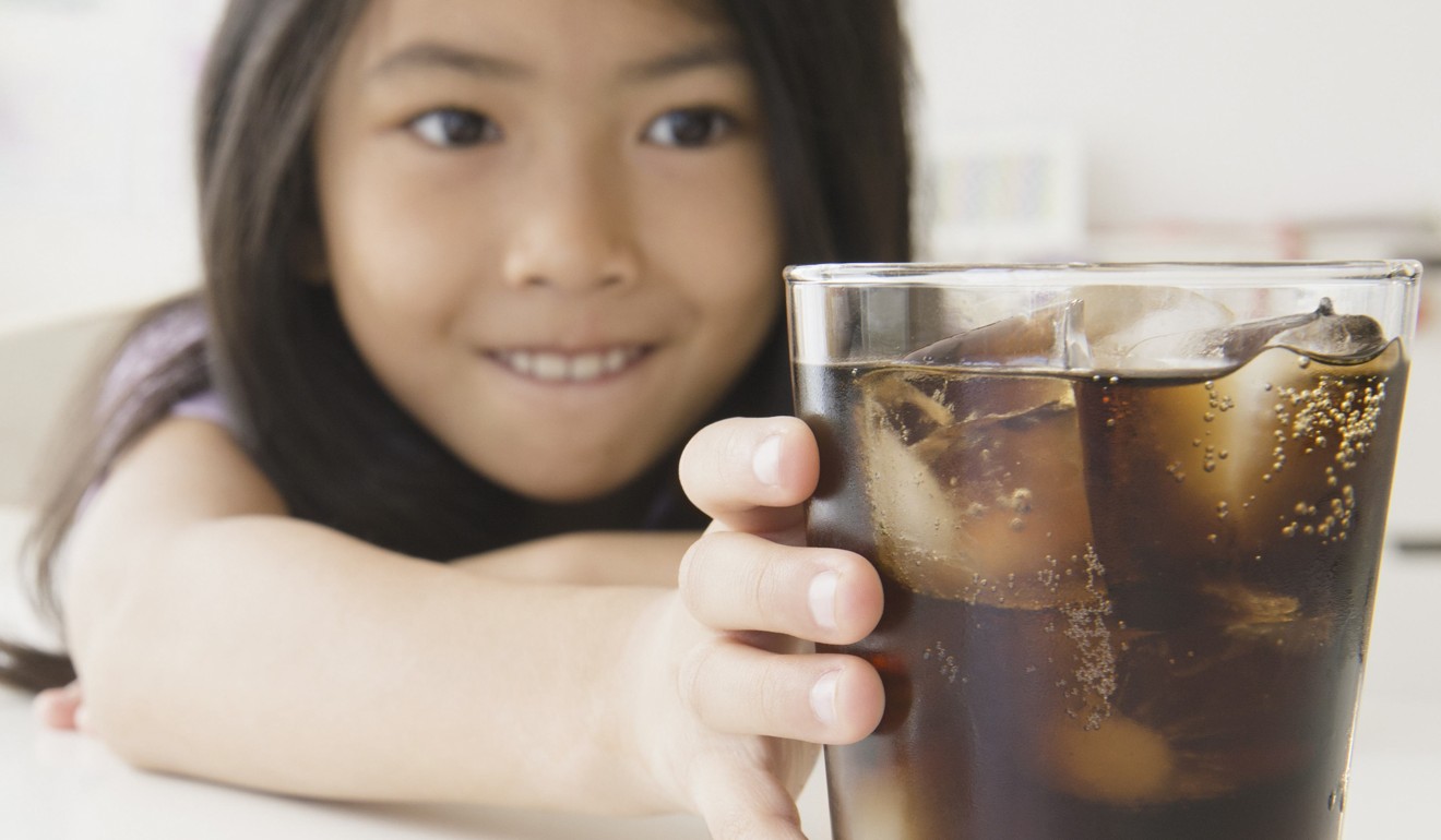 A girl reaches for a soft drink. Such drinks should be taxed to reduce their consumption, say health professionals in a series of studies. Photo: Alamy