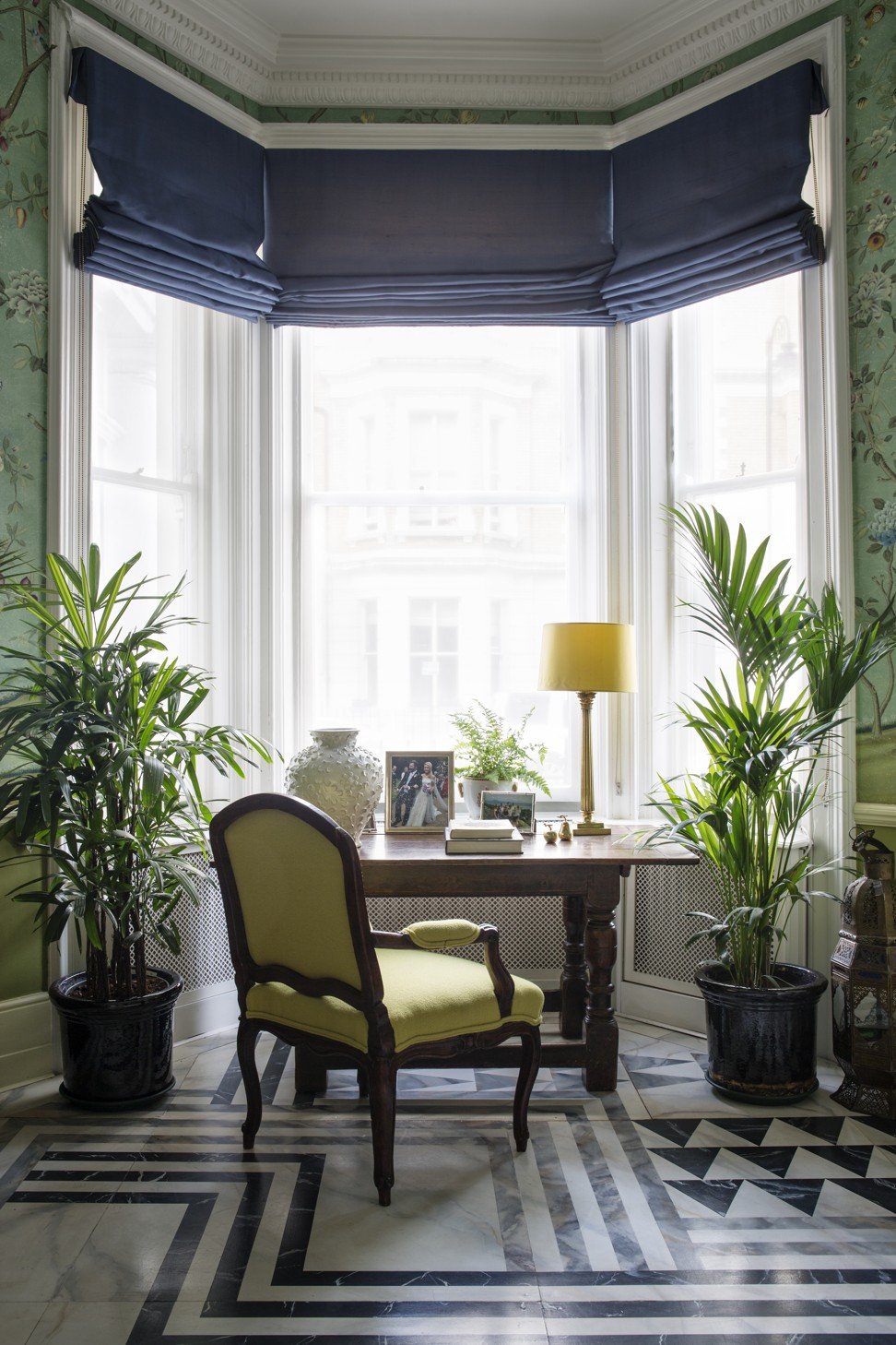 Plenty of light comes in through the large windows, and plants are everywhere. The geometric-print marble floor makes a beautiful contrast with the wallpaper. 