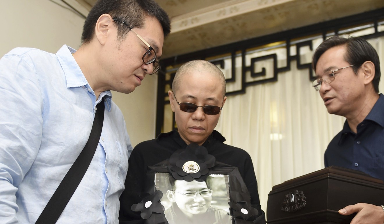 Widow Liu Xia (centre) holds a photo of her late husband Liu Xiaobo during his funeral in Shenyang in northeastern China's Liaoning province. Photo: AP