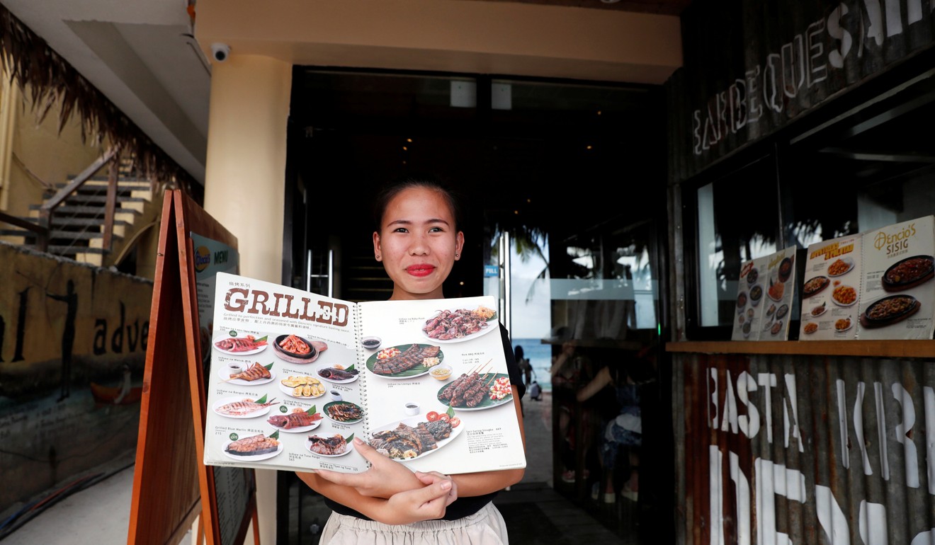 A waitress displays the menu at the entrance of a restaurant in Boracay. Photo: Reuters