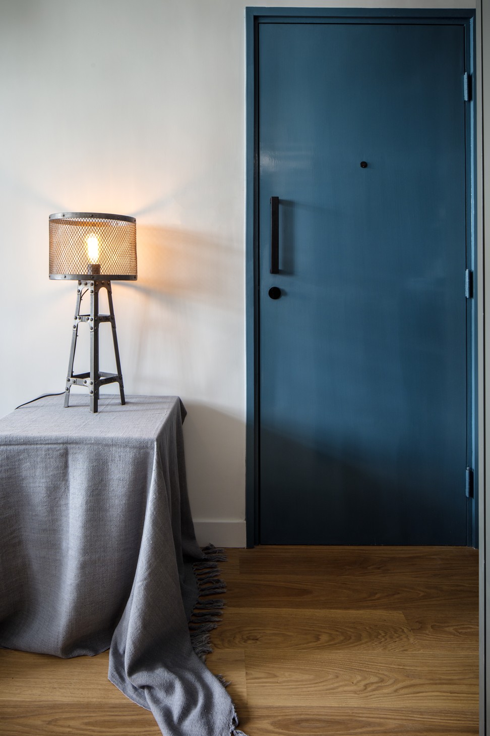 Blue and grey tones give the apartment a cool, industrial feel, which is softened by the engineered wood floors.