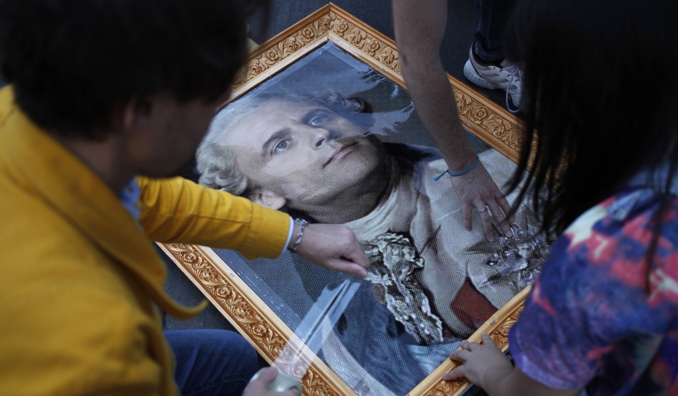 Protesters frame a picture of French President Emmanuel Macron depicted as King Louis XVI during a protest in Paris, France on Saturday. Photo: AP Photo