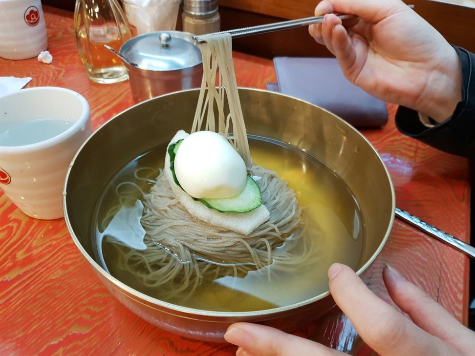 A Korea Times staff member tries Pyongyang naengmyeon at a restaurant in Jung-gu, central Seoul. The noodles are made with buckwheat. In South Korea, cold noodles are served in a clear beef broth. Photo: Korea Times