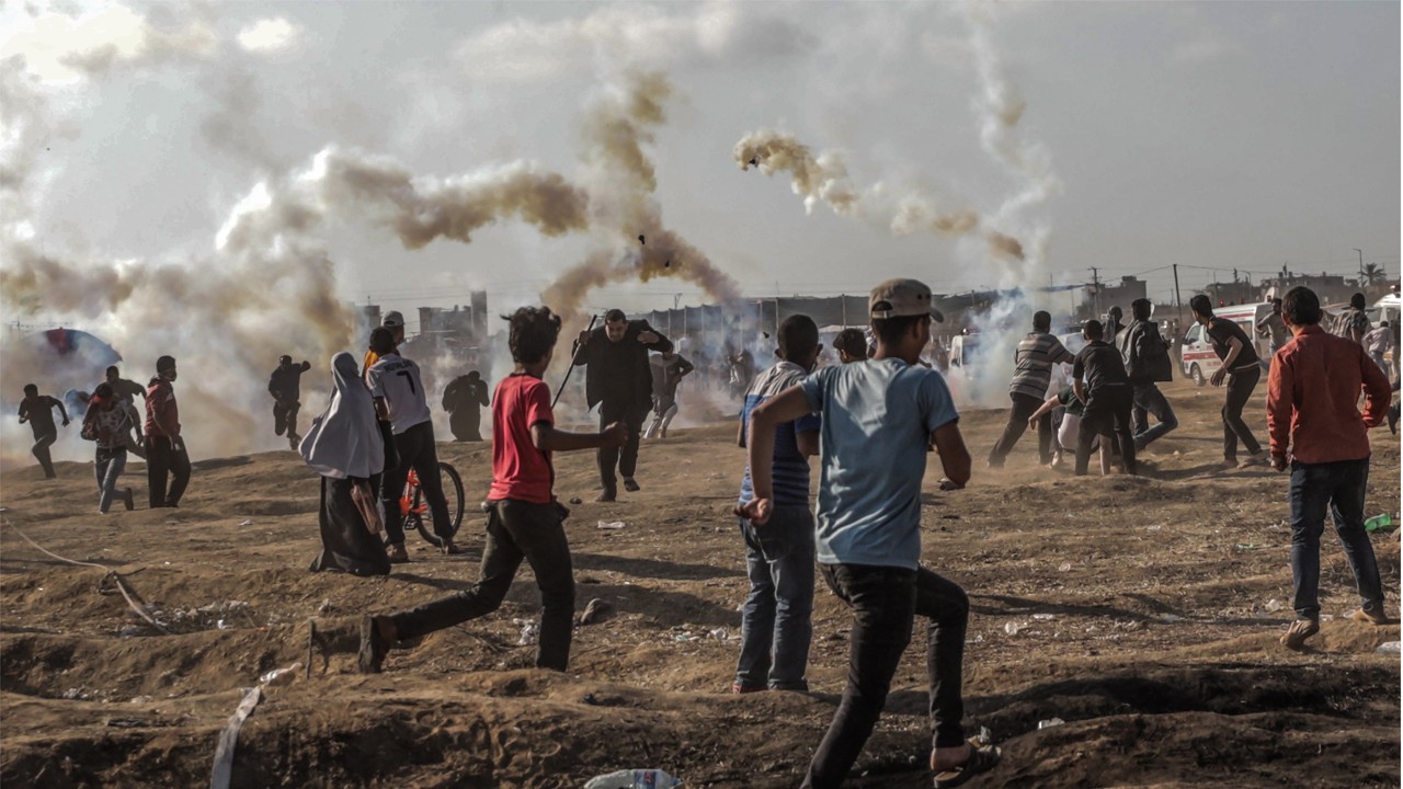 Palestinian protesters run for cover from Israeli tear-gas during clashes near the border with Israel in Gaza on Tuesday. Photo: EPA-EFE 
