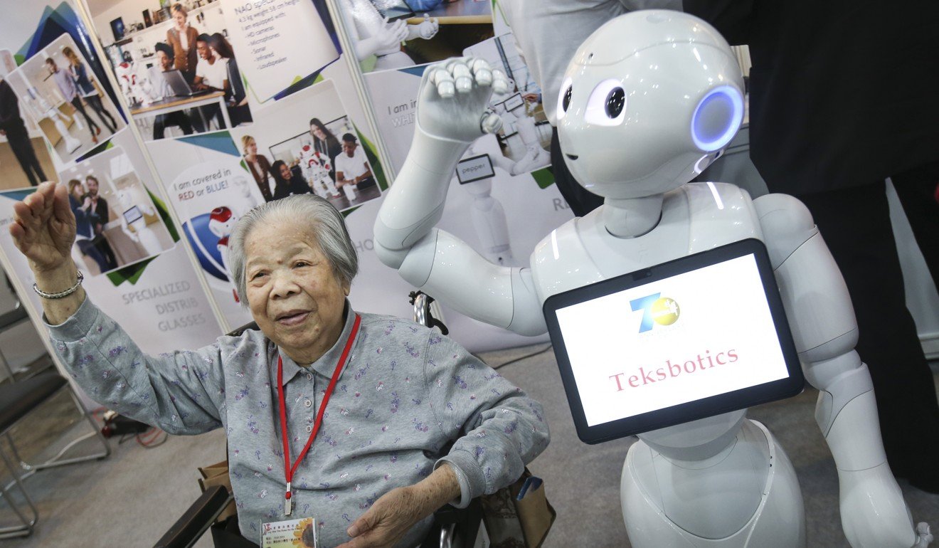 An elderly lady follows dance steps of an intelligent robot, at the Gerontech and Innovation Expo Summit in Hong Kong. Photo: SCMP