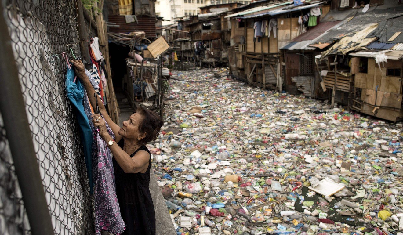Perigrina Santos, 81, collects her laundry next to a garbage-filled creek in Manila. The blanket of trash on a creek that flows between the makeshift homes of a Manila slum is so dense it appears one could walk across it like a paved street. Photo: AFP