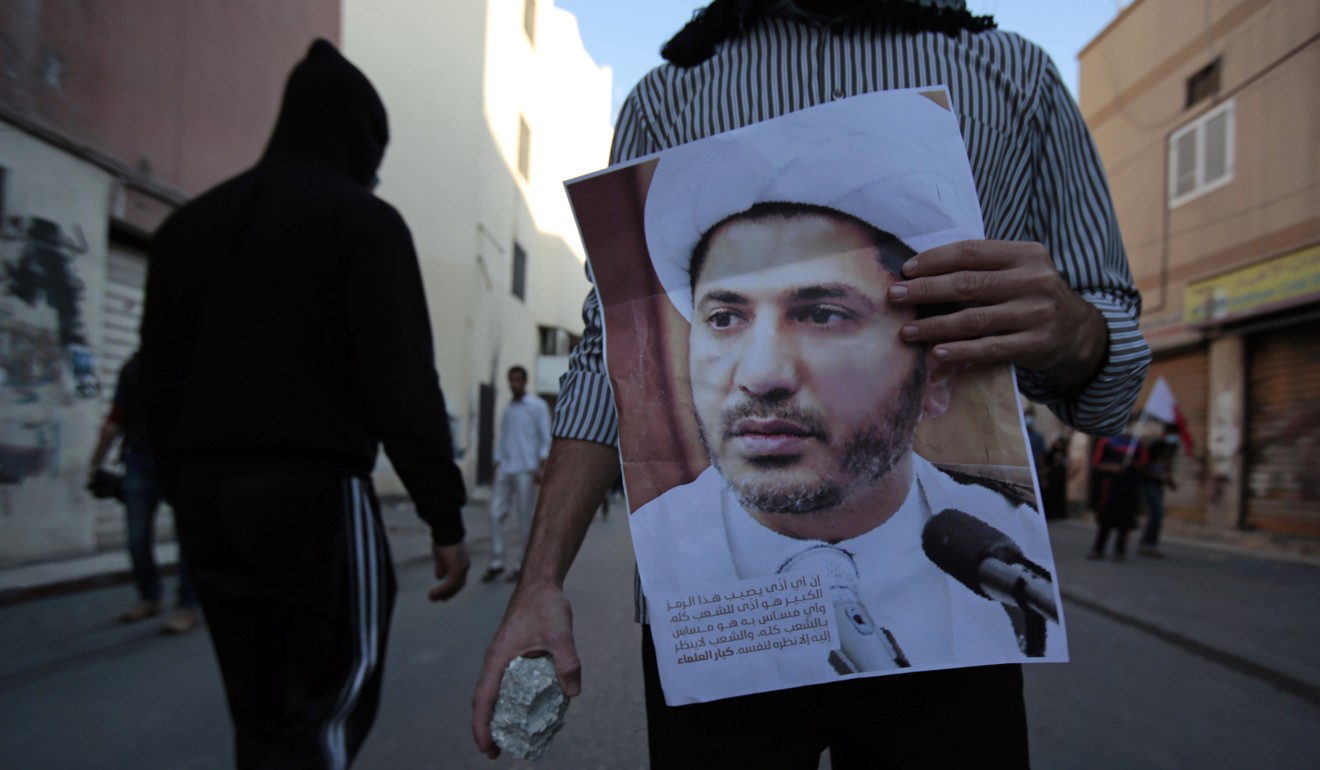 A Bahraini anti-government protester holding a stone and a picture of Sheikh Ali Salman. Photo: AP