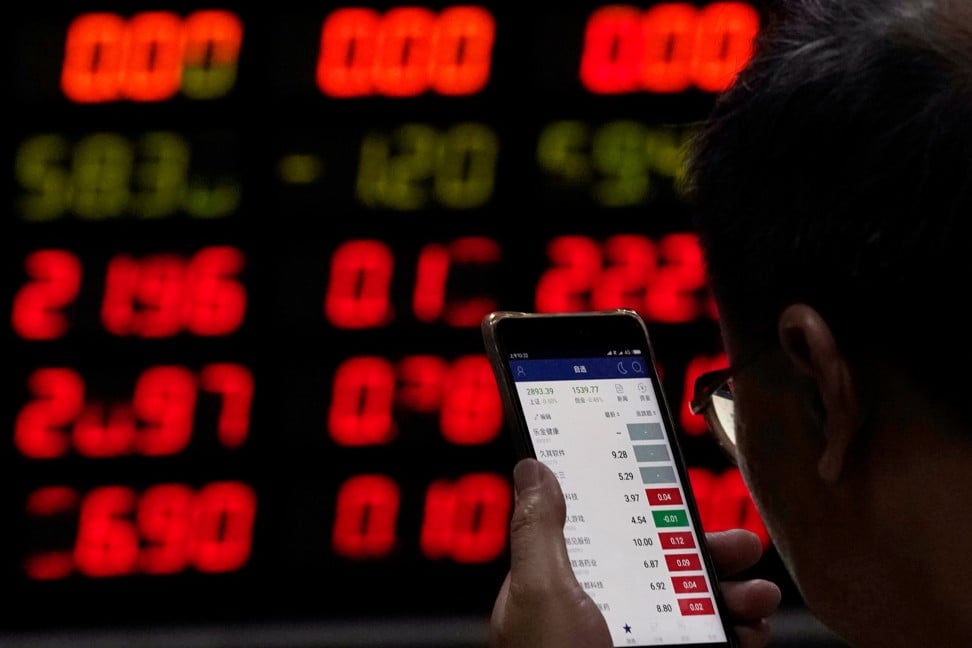 An investor checks stock information on a mobile phone at a brokerage house in Shanghai, China on Wednesday. Photo: Reuters