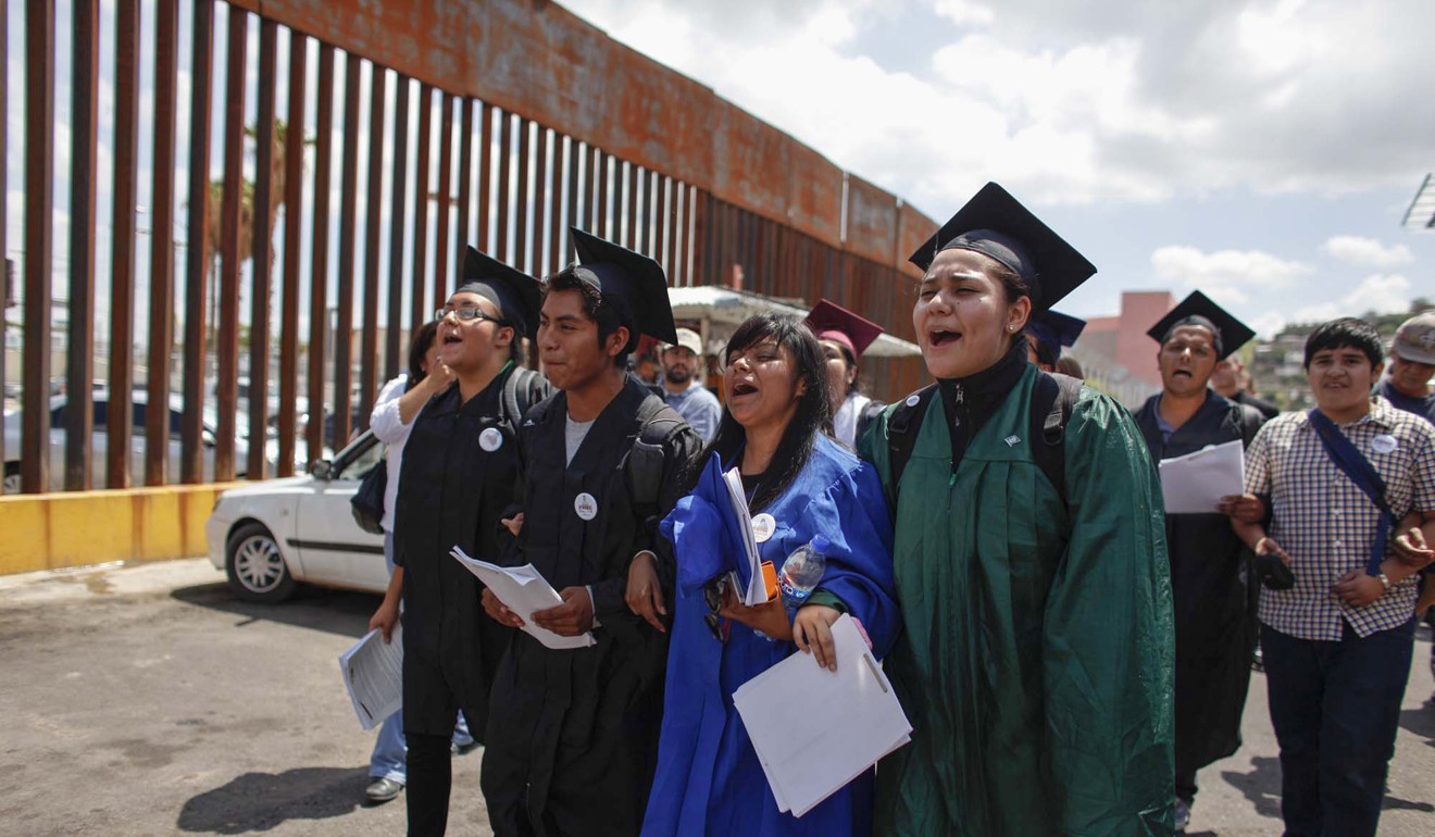 Demonstrators, wearing graduation caps and gowns to show their desire to finish school in the US, march with linked arms to the US port of entry in Nogales, Mexico, where they planned to request humanitarian parole on Friday. Photo: AP