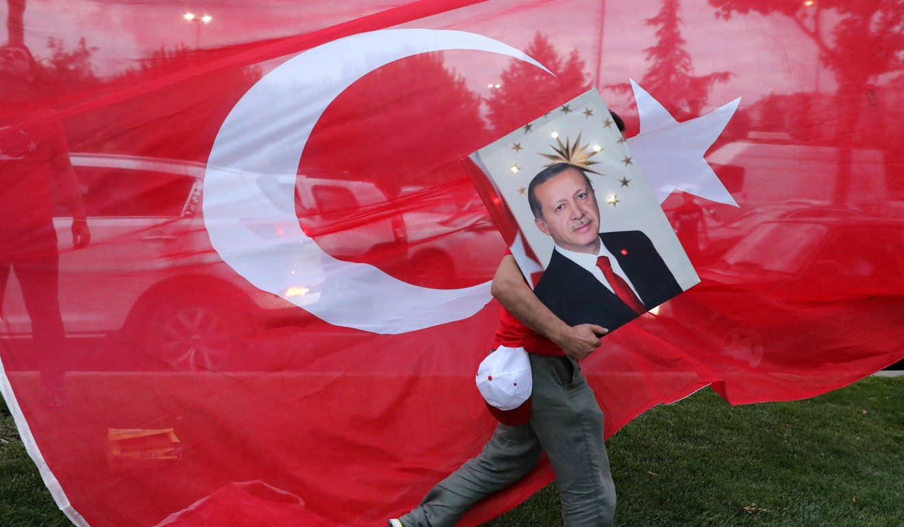 A supporters of Turkish President Tayyip Erdogan holds his picture in front of a Turkish flag. Photo: Reuters
