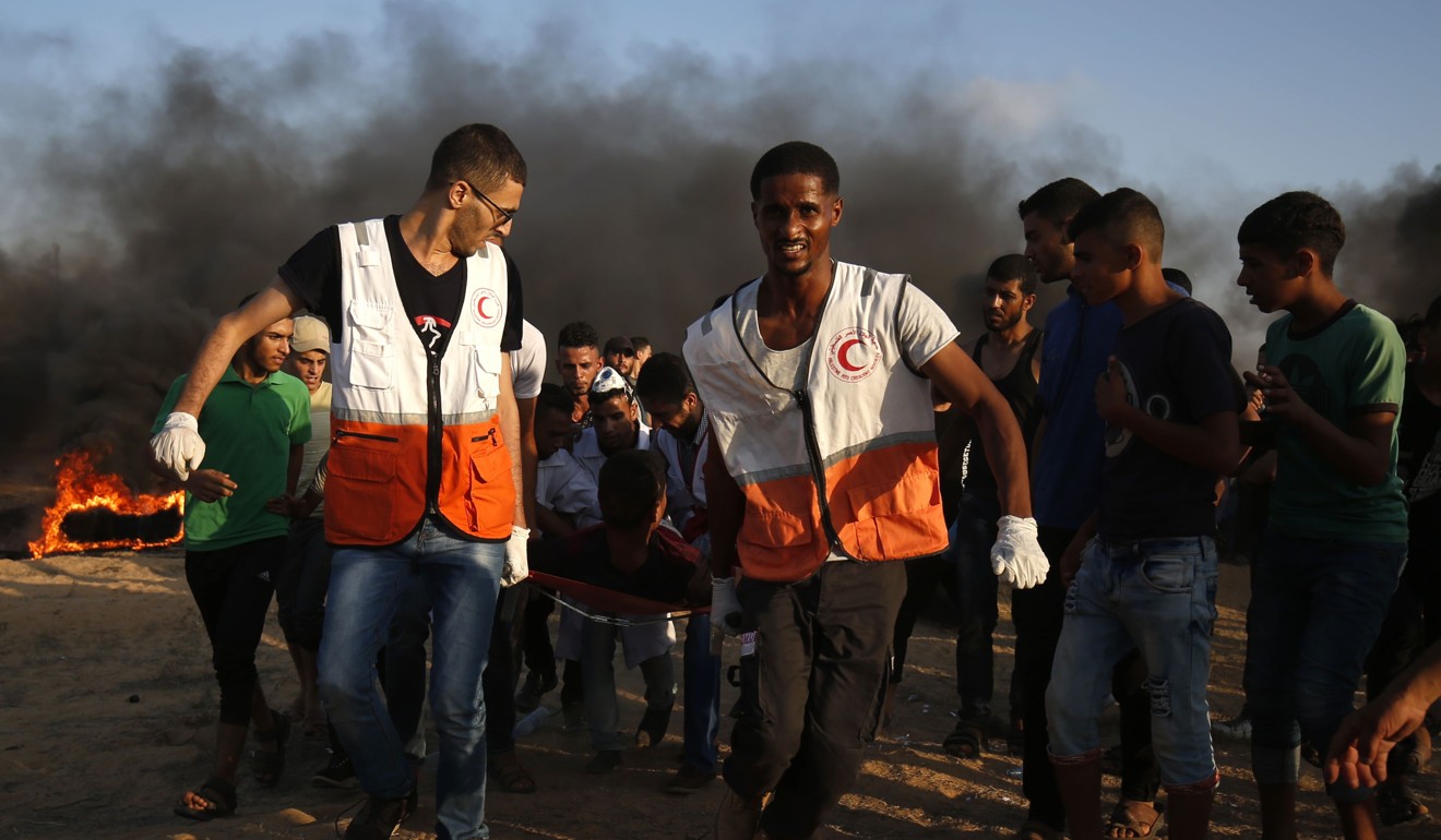 Palestinian protesters and rescuers carrying a wounded person. Photo: AFP