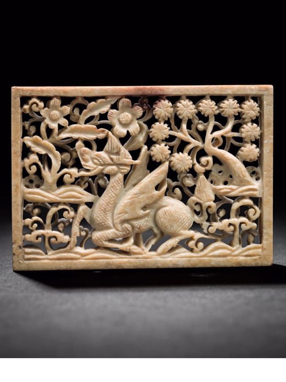 A Chinese jade belt plaque with the carving of a dragon, which is a symbol of the emperor and the heavens.