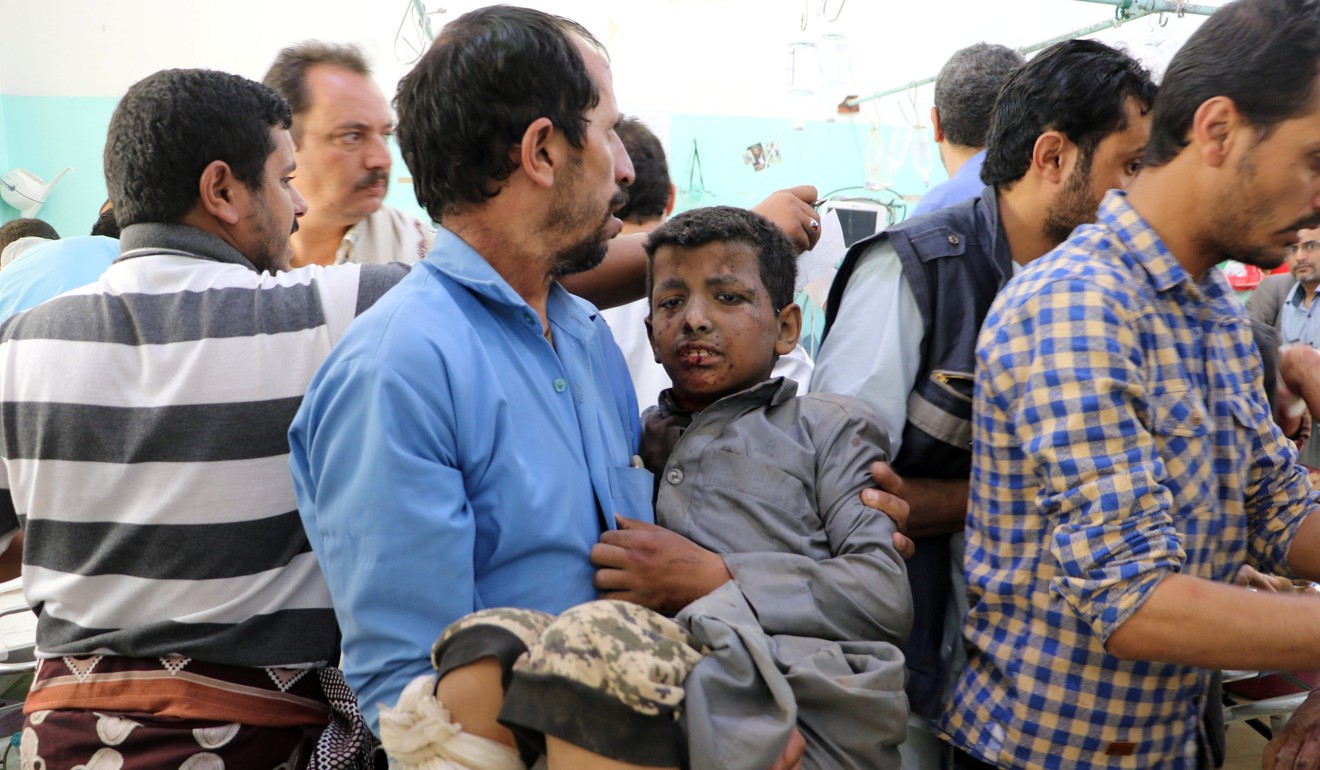 A Yemeni man holds a boy who was injured. Photo: Reuters