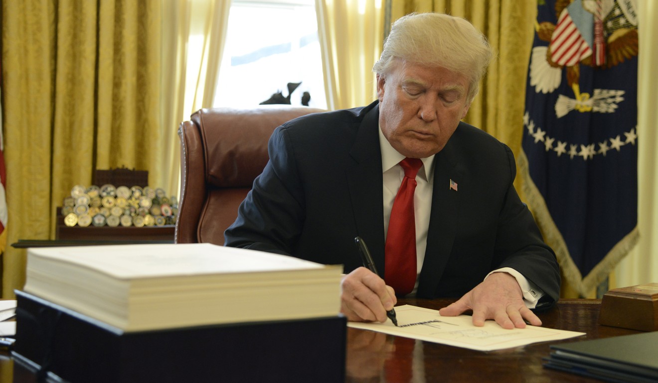 United States President Donald J. Trump signs the US$1.5 trillion tax cut bill in the Oval Office of the White House on December 22, 2017, in Washington. Though credited with boosting consumer spending and stimulating growth, the tax cut has also been blamed for greatly increasing the fiscal deficit. Photo: CNP / Zuma Press / TNS