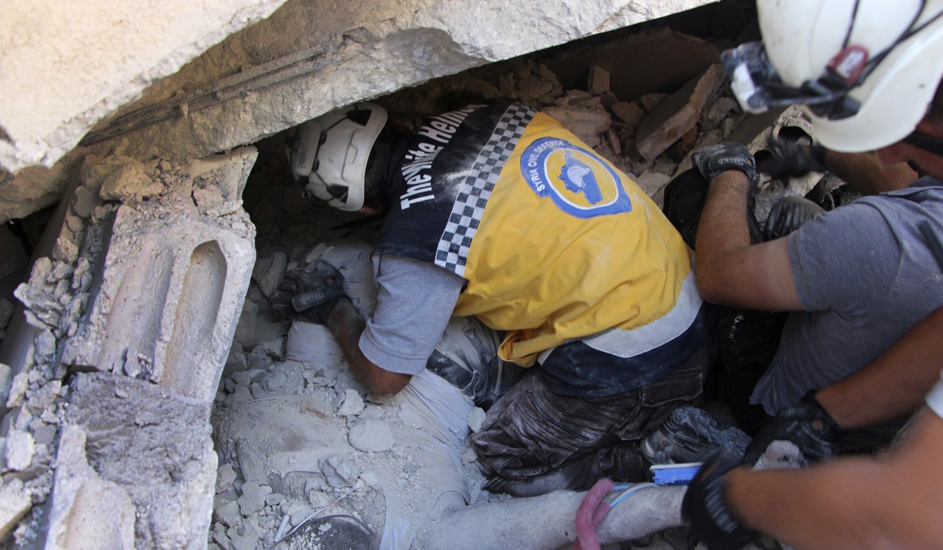 Syrian Civil Defence White Helmets remove a body from the rubble. Photo: AP