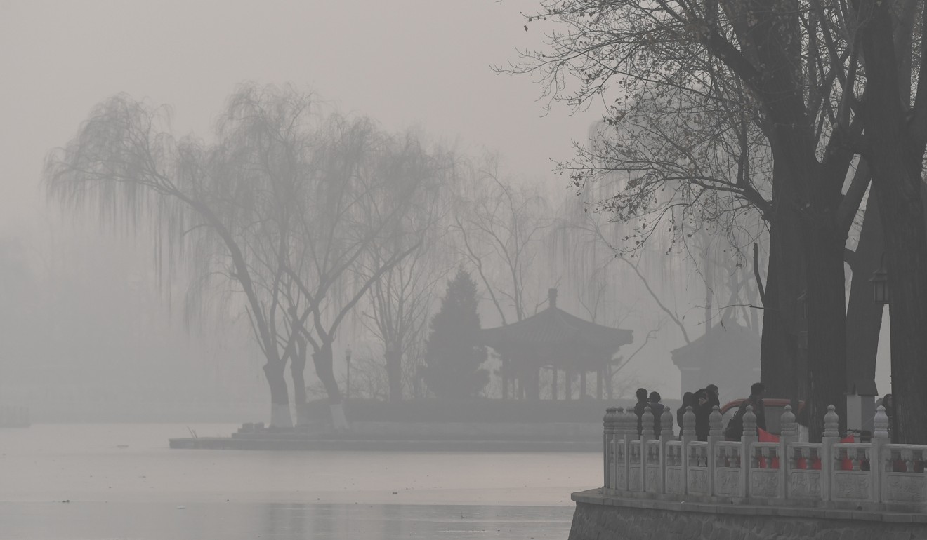 Visitors walk beside a lake on a heavily polluted day in Beijing on January 1, 2017. Photo: AFP