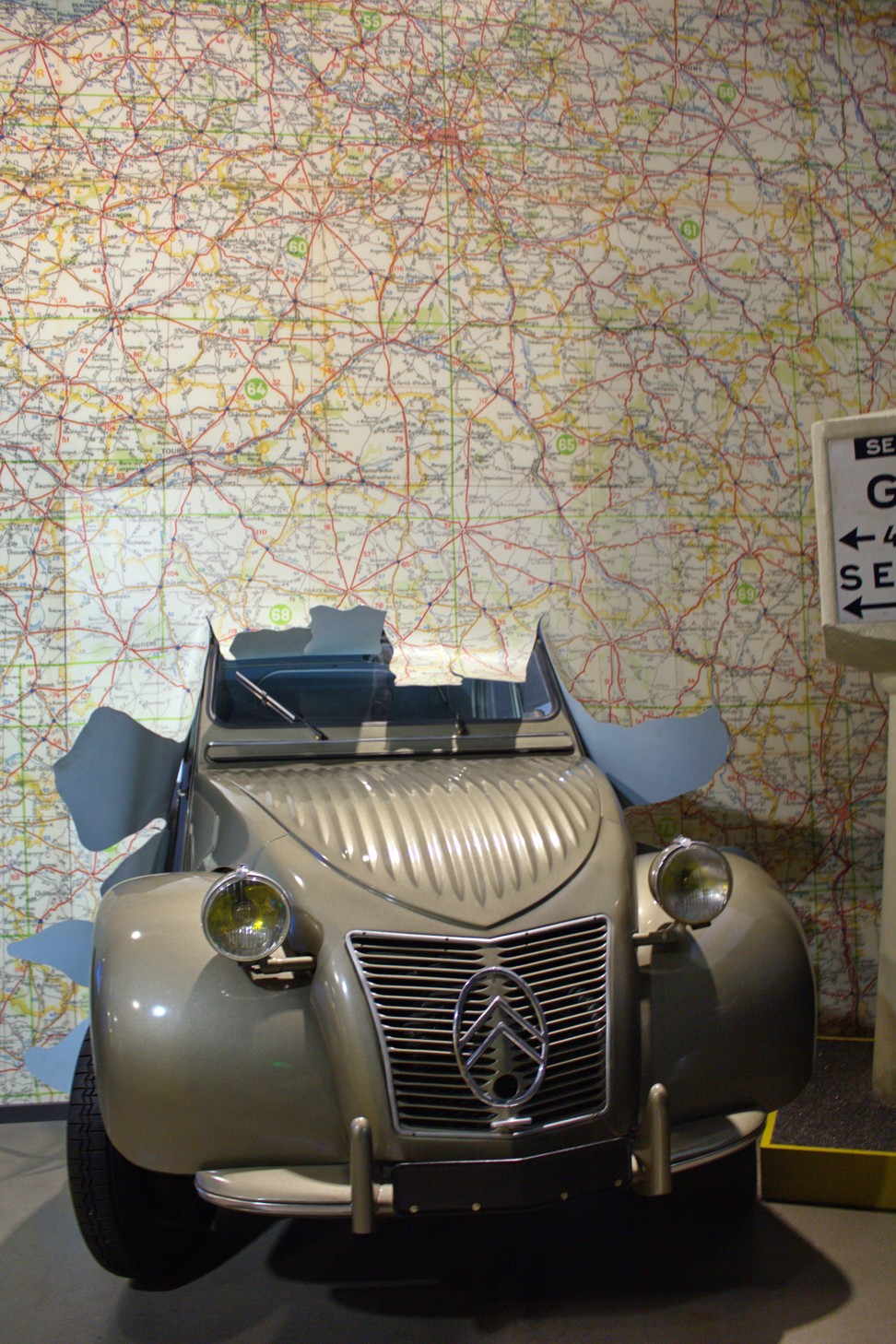 A Citroën 2CV smashes through a Michelin road map at L’Aventure Michelin.