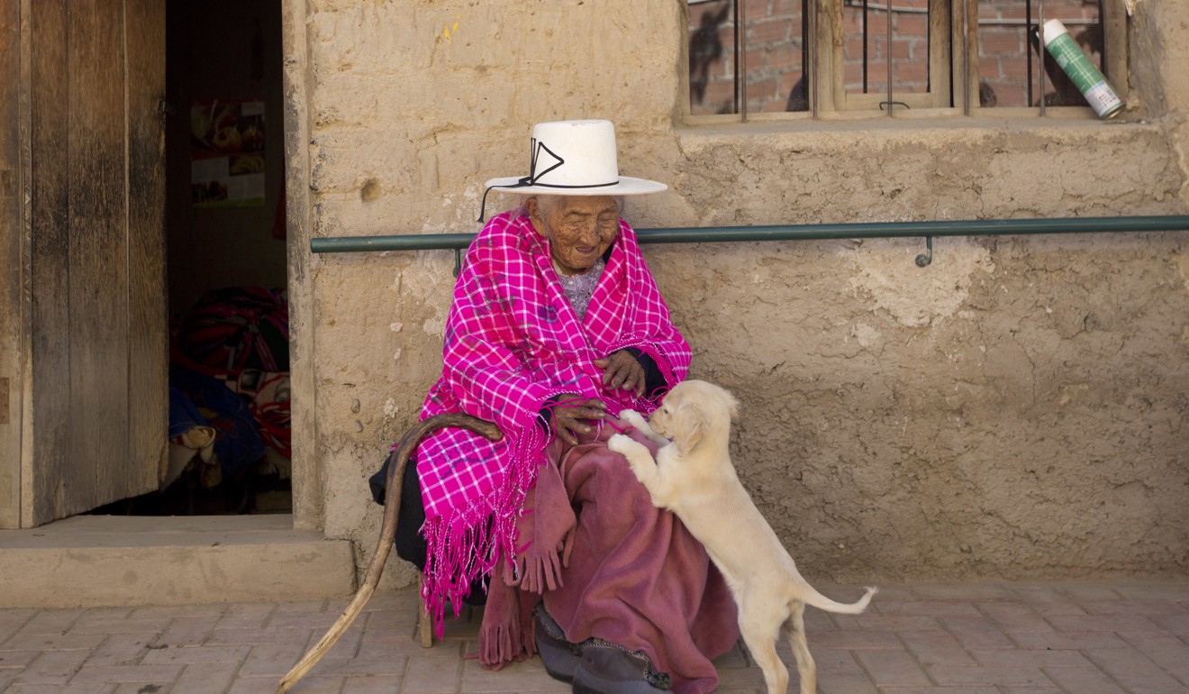 Julia Flores Colque plays with Chiquita, a family pet, outside her home in Sacaba, Bolivia. Photo: AP