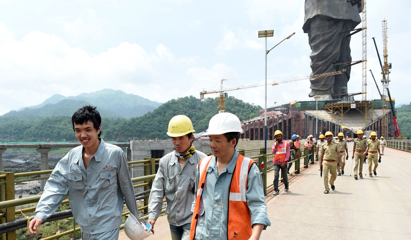 Chinese workers walking by the ‘Statue of Unity’. Photo: AFP
