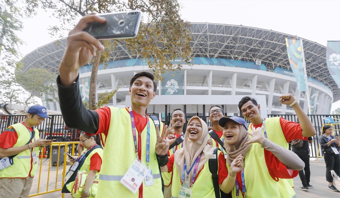 Volunteers take a selfie outside Gelora Bung Karno Stadium in Jakarta. Photo: Kyodo