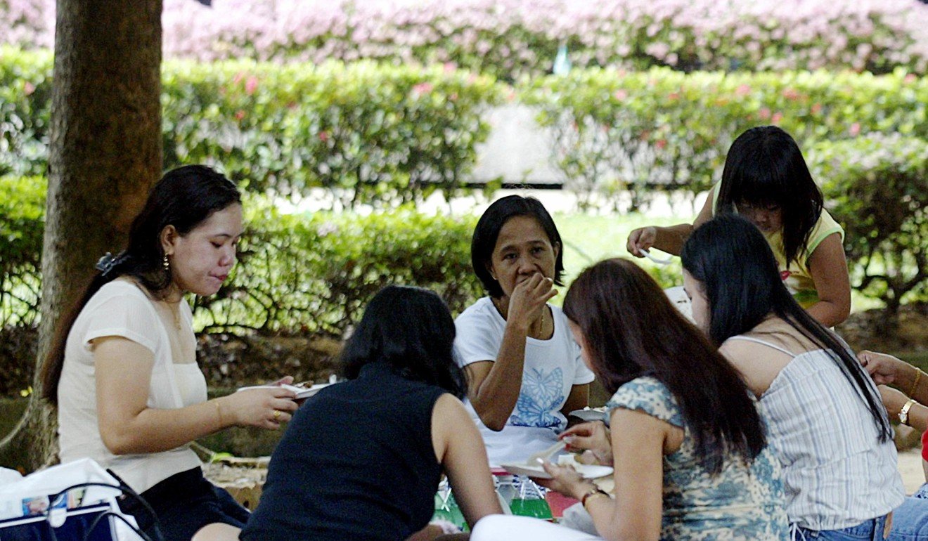Domestic helpers enjoying a picnic in the shade at Gulung-gulung park in Singapore. Rights groups slammed adverts on a Singapore website selling Indonesian domestic helpers. Photo: AFP