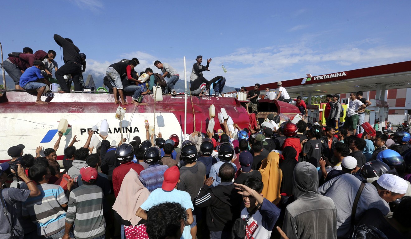 People take petrol from a fuel truck in Palu. Photo: AP