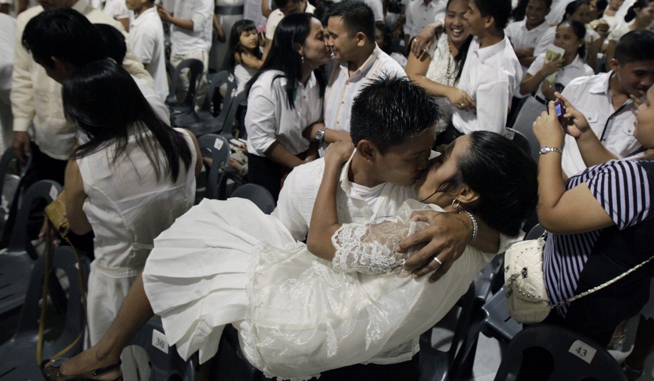 A Filipino groom kisses his new bride at a mass wedding in December 2012. Divorce is illegal in the overwhelmingly Catholic country, with marriages only ending in legal separation, which does not allow remarriage, or annulment, which is costly. Photo: EPA