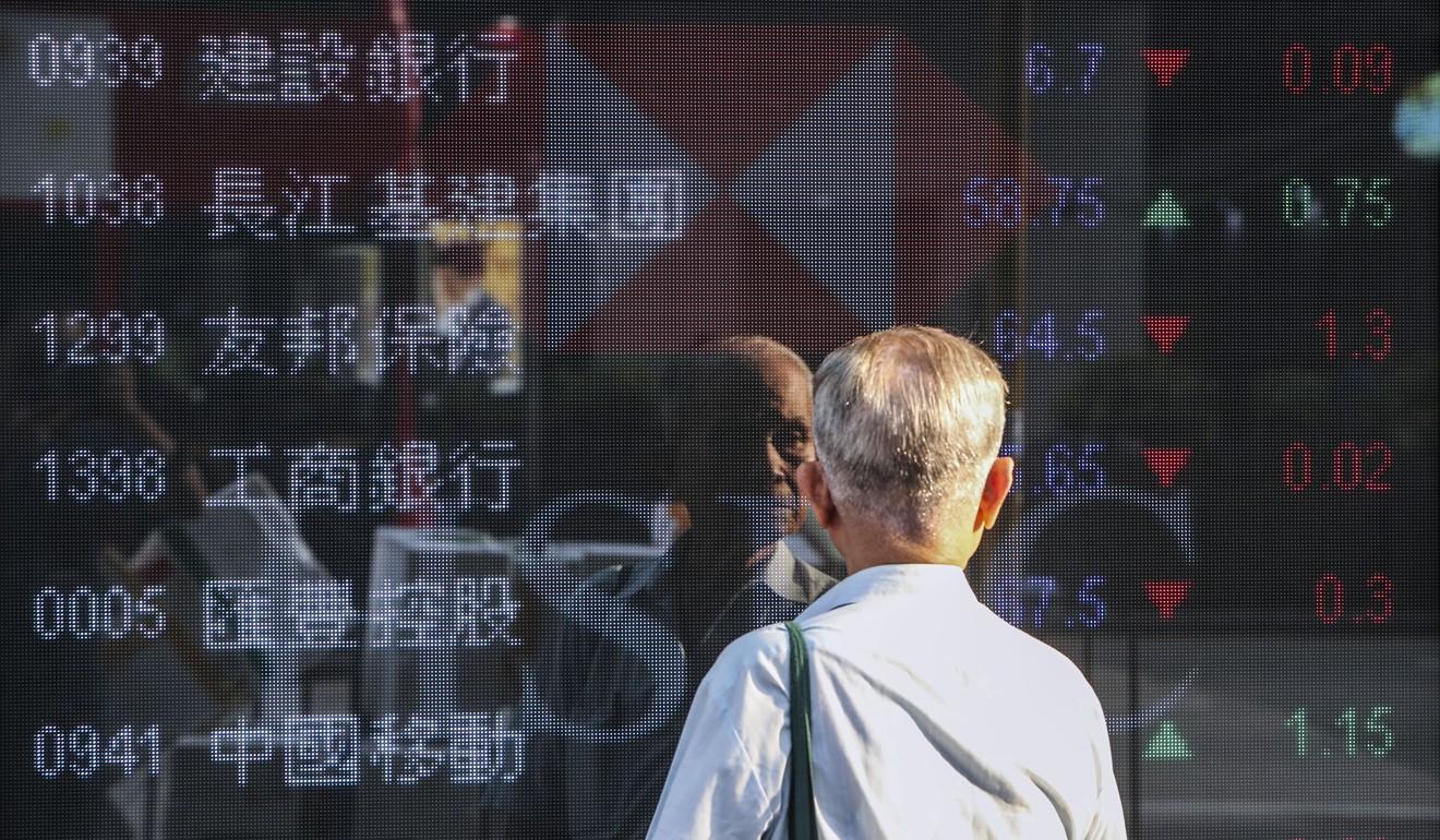 An elderly investor checks the stock prices in Mong Kok. Photo: Winson Wong