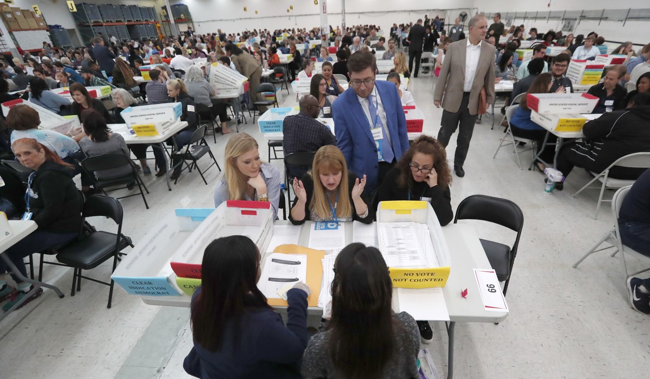 Workers at the Broward County Supervisor of Elections office show Republican and Democrat observers ballots during a hand recount in Lauderhill. Photo: AP Photo