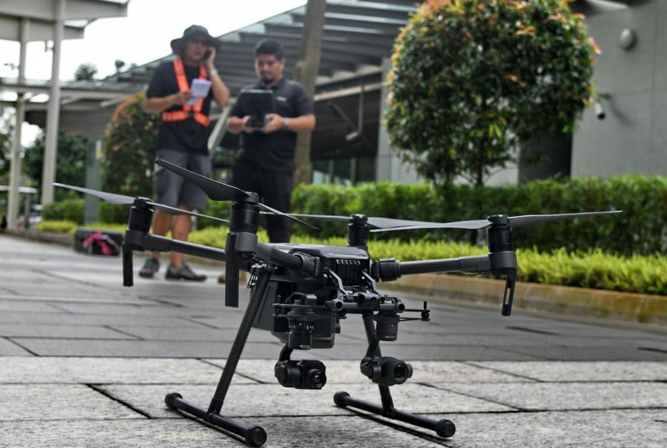 Staff members of Singapore technology firm H3 Dynamics preparing to fly a drone to inspect a building facade in Singapore. Image: AFP