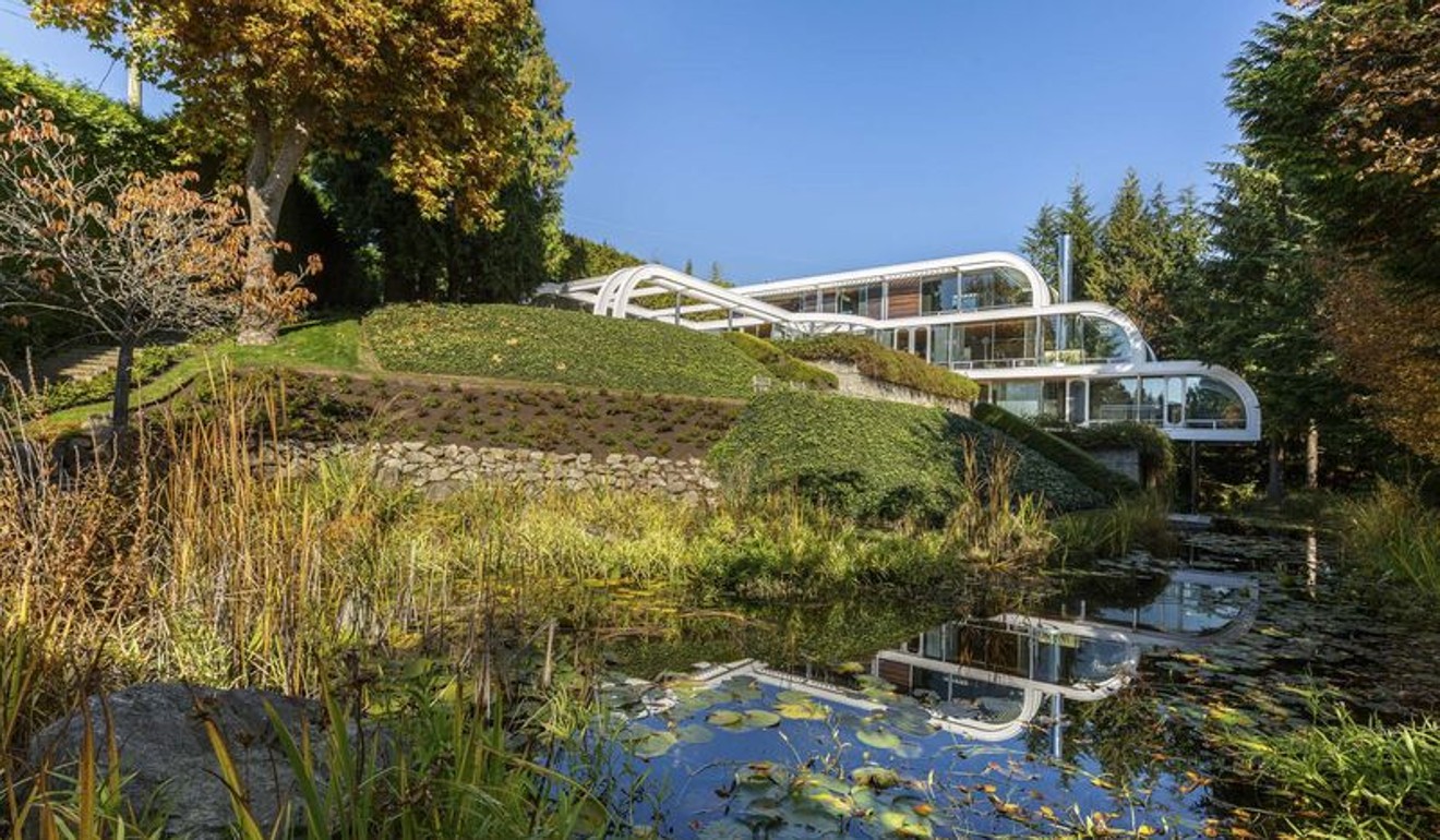 The three-storey house is set on a terraced hillside with multiple water features.