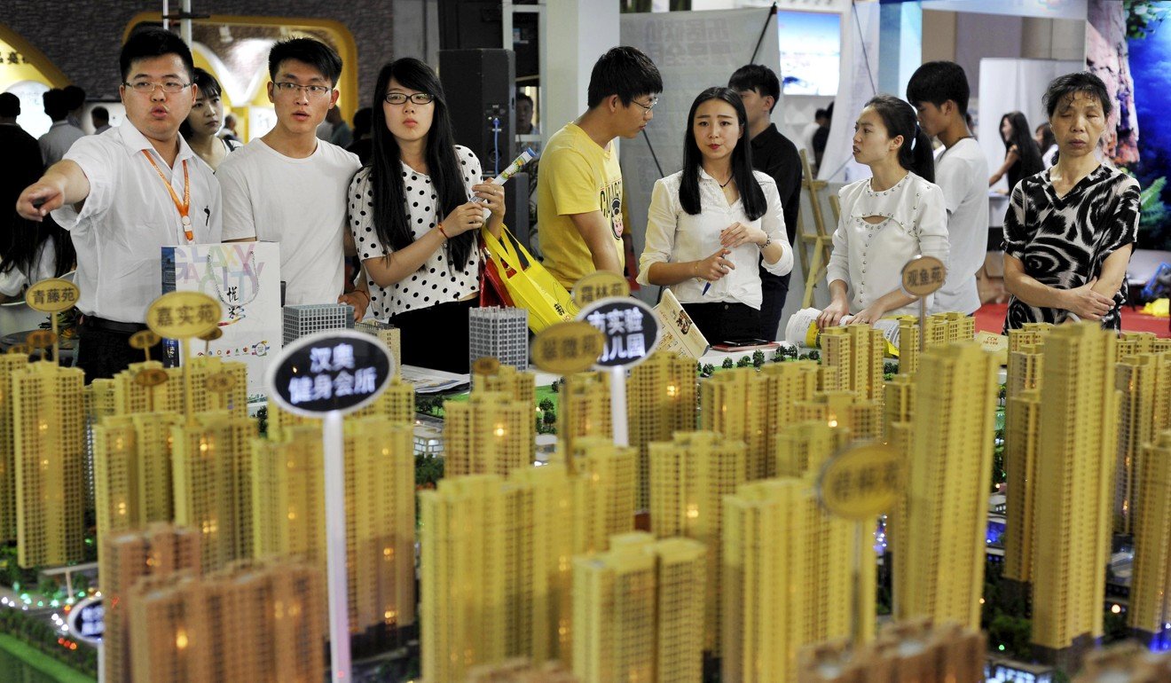 Sales representatives talk to potential buyers in front of a model of a residential complex at a real estate exhibition in Wuhan, Hubei province, in China on May 10, 2015. Photo: Reuters