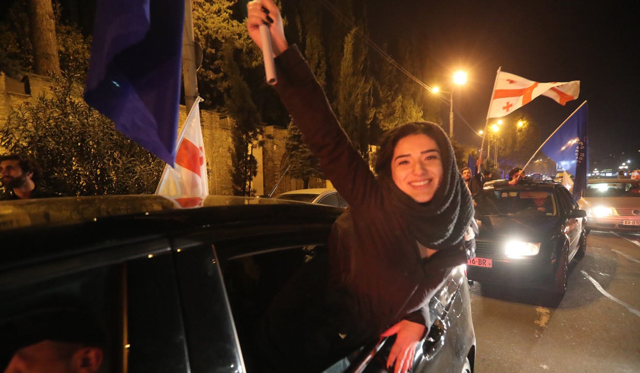 Supporters of independent presidential candidate Salome Zurabishvili, who is backed by the ruling Georgian Dream party, wave the party's flags and Georgian flags while riding a car as they celebrate after announcement of the exit polls. Photo: EPA-EFE