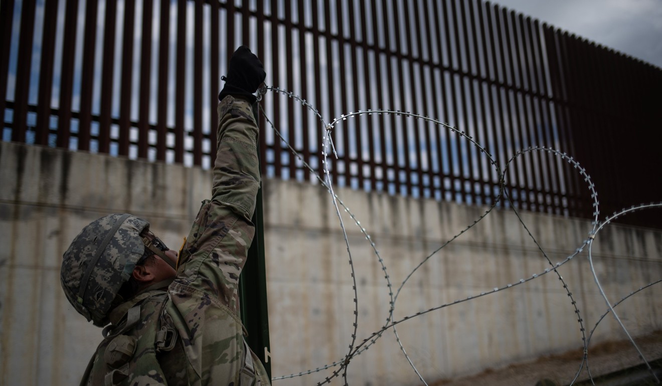 The border fence is seen in the background as a US Army soldier installs concertina wire along the US-Mexico border in Hidalgo, Texas, on November 8. Photo: Reuters