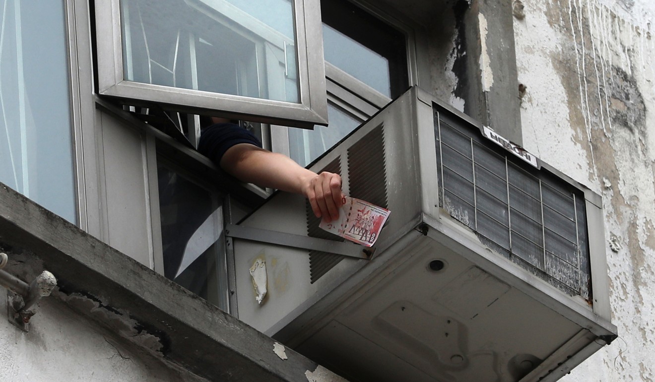 A HK$100 note is retrieved by a resident in Sham Shui Po on Saturday. Photo: Sam Tsang