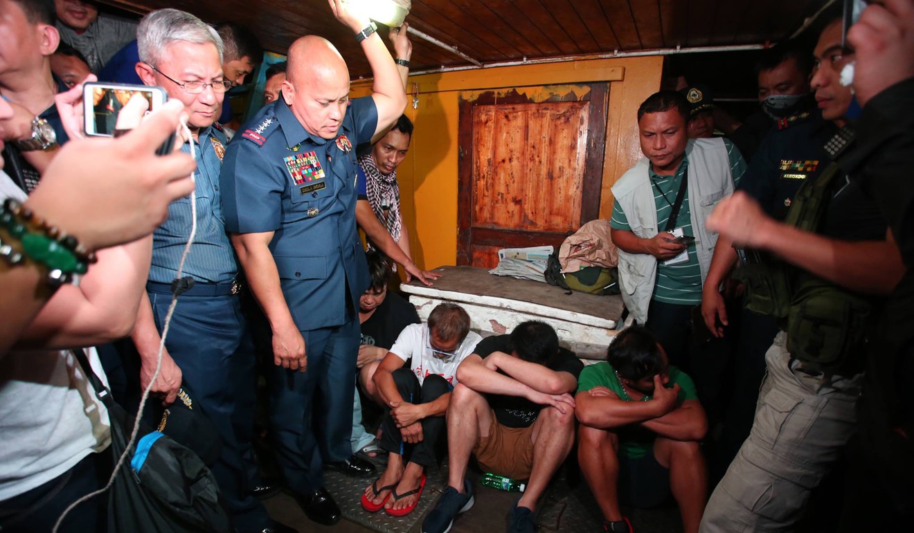 The group (pictured sitting) were detained in July 2016 on board a 50-metre fishing boat about 3km off the coast of Zambales province, northwest of Manila. Photo: Handout