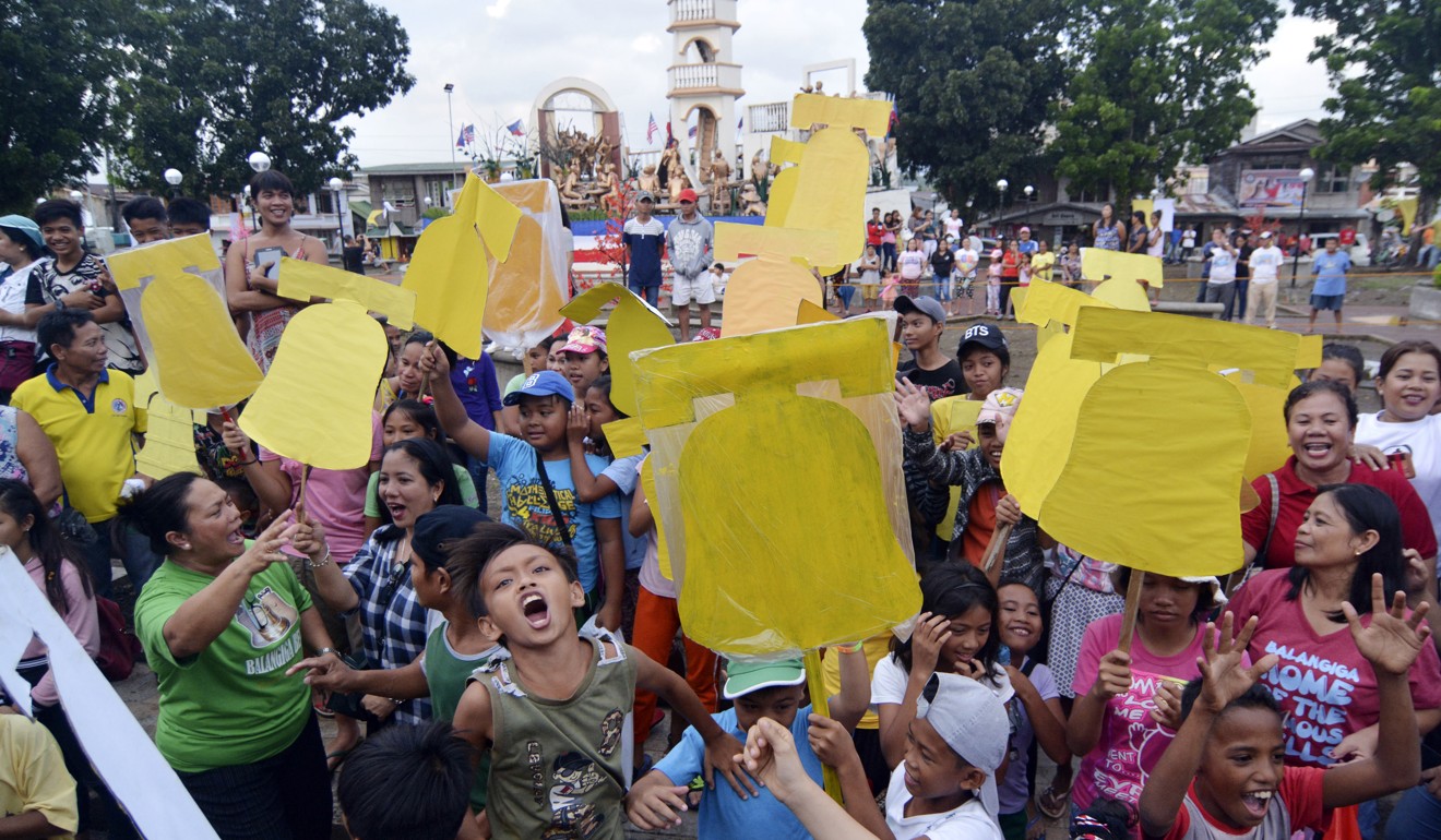Children waving bell-shaped cut-outs cheer as they welcome the bells back to Balangiga. Photo: AP Photo